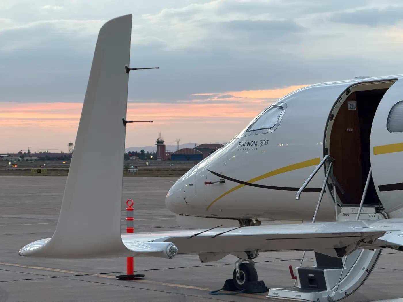 A Phenom 300 on the ramp at sunset, door open