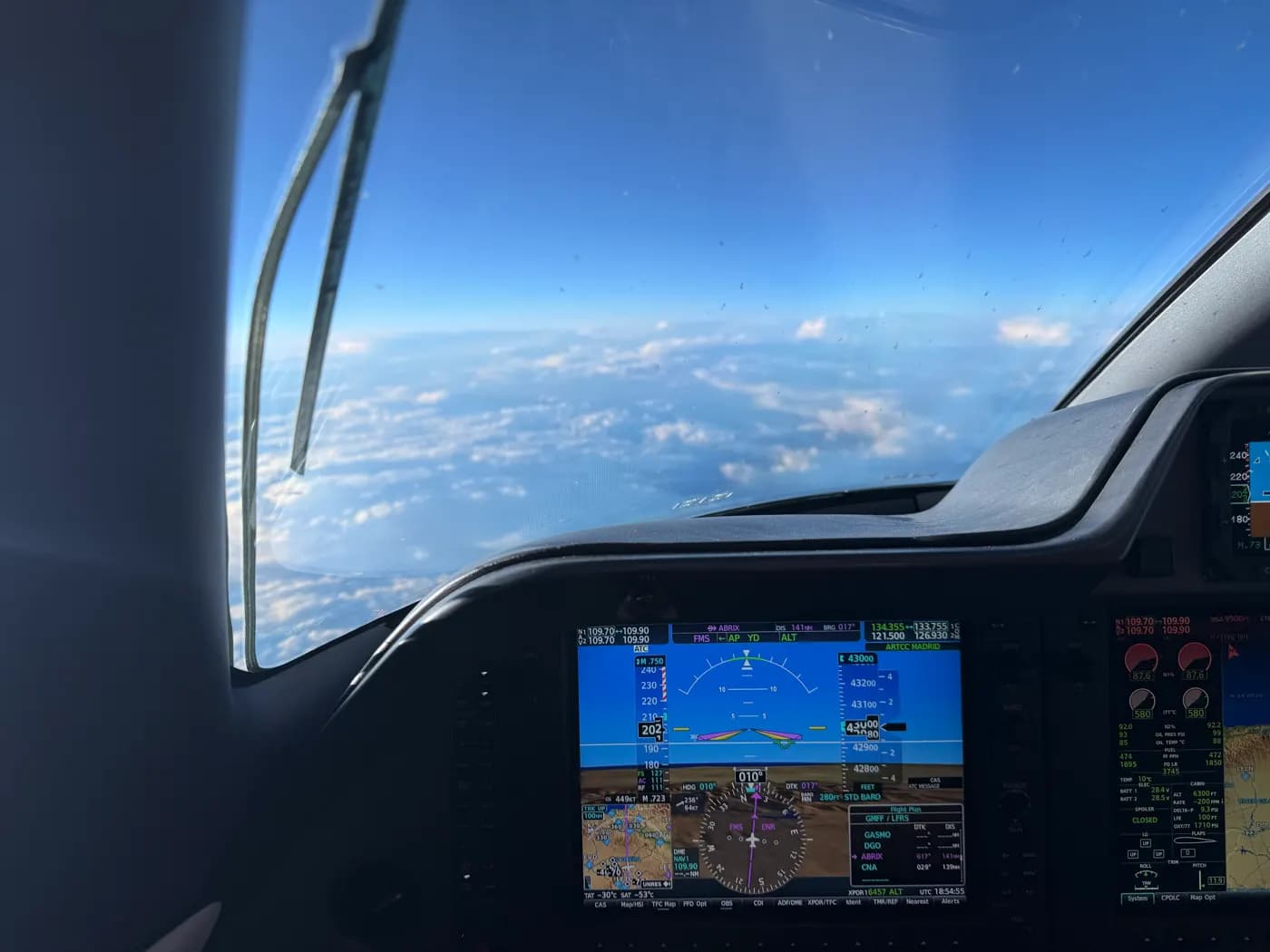 Phenom 300 cockpit in cruise above the clouds