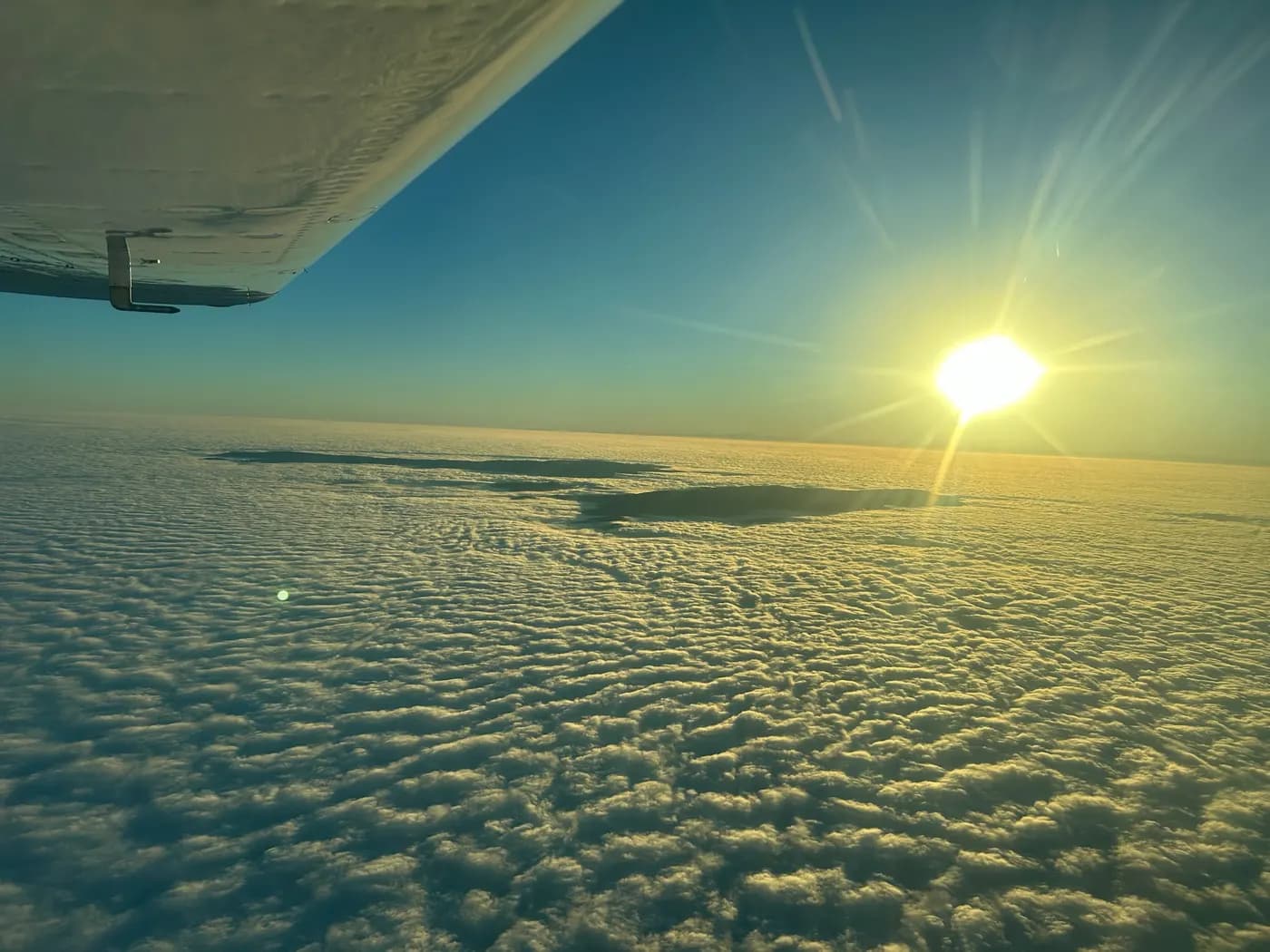 The sun over a sea of clouds, under the wing