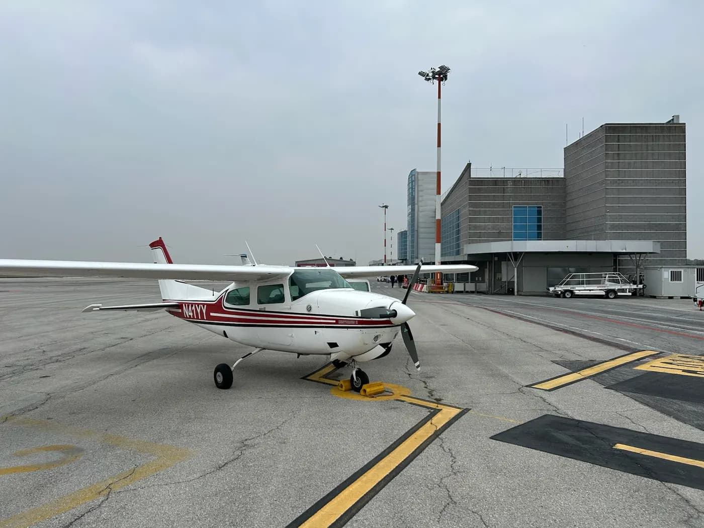 A high-wing aircraft parked in front of a terminal